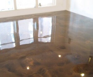 A shiny, polished, dark brown anti-slip epoxy floor reflects windows and ceiling lights in an empty, bright room with white walls. A shiny, polished, dark brown anti-slip epoxy floor reflects windows and ceiling lights in an empty, bright room with white walls.