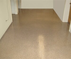 A room with smooth, glossy, light brown epoxy flooring Connecticut, white walls, an open doorway, and a visible power outlet on the left wall. A room with smooth, glossy, light brown epoxy flooring Connecticut, white walls, an open doorway, and a visible power outlet on the left wall.