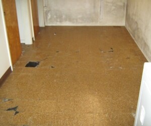 A room with brown, worn-out linoleum flooring, patches of missing or damaged tiles, off-white walls, and a washer partially visible in the lower right corner. Perfect candidate for durable resinous flooring CT to revitalize and protect the space. A room with brown, worn-out linoleum flooring, patches of missing or damaged tiles, off-white walls, and a washer partially visible in the lower right corner. Perfect candidate for durable resinous flooring CT to revitalize and protect the space.