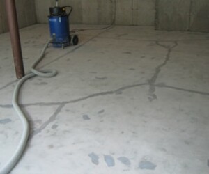 A concrete basement floor with visible repaired cracks suggests the need for industrial floor coating; a vacuum cleaner and hose are on the unfinished surface, with raw concrete walls in the background. Consider epoxy flooring Connecticut for a durable finish. A concrete basement floor with visible repaired cracks suggests the need for industrial floor coating; a vacuum cleaner and hose are on the unfinished surface, with raw concrete walls in the background. Consider epoxy flooring Connecticut for a durable finish.