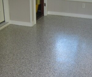 A close-up view of a room with smooth, speckled gray USDA approved flooring, light gray walls with white trim, and an open doorway leading to another room. A close-up view of a room with smooth, speckled gray USDA approved flooring, light gray walls with white trim, and an open doorway leading to another room.