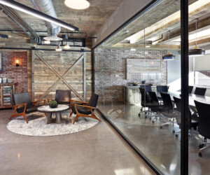 Modern office with a rustic lounge area featuring wooden chairs and a round table on a rug, next to a glass-walled conference room with black chairs. Industrial ceilings, brick walls, and epoxy flooring Connecticut complete the look. Modern office with a rustic lounge area featuring wooden chairs and a round table on a rug, next to a glass-walled conference room with black chairs. Industrial ceilings, brick walls, and epoxy flooring Connecticut complete the look.