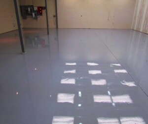 A freshly coated, glossy gray epoxy floor in an empty industrial space with beige walls, exposed beams, and reflected lights on the shiny surface showcases premium epoxy flooring Connecticut. A freshly coated, glossy gray epoxy floor in an empty industrial space with beige walls, exposed beams, and reflected lights on the shiny surface showcases premium epoxy flooring Connecticut.