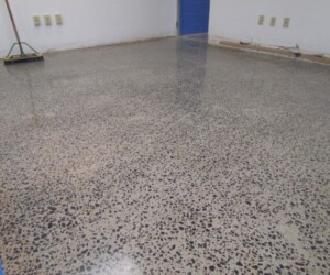 A polished concrete floor with a speckled, exposed aggregate finish in an empty room showcases the sleek look often sought in epoxy flooring Connecticut projects. A broom leans against the wall, and electrical outlets line the crisp white walls. A polished concrete floor with a speckled, exposed aggregate finish in an empty room showcases the sleek look often sought in epoxy flooring Connecticut projects. A broom leans against the wall, and electrical outlets line the crisp white walls.