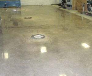 A smooth, polished concrete floor with circular utility access points, reflecting ceiling lights—ideal for commercial kitchen flooring—in an industrial or commercial interior space under construction or renovation. A smooth, polished concrete floor with circular utility access points, reflecting ceiling lights—ideal for commercial kitchen flooring—in an industrial or commercial interior space under construction or renovation.