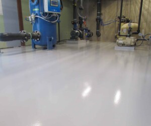 A smooth, shiny anti-slip epoxy floor reflects the overhead lighting in this utility room, featuring various pumps, pipes, and machinery along the walls. A smooth, shiny anti-slip epoxy floor reflects the overhead lighting in this utility room, featuring various pumps, pipes, and machinery along the walls.