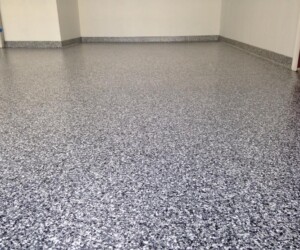 A room with smooth, glossy gray and black speckled epoxy flooring Connecticut residents love, white walls, and gray base trim along the bottom edge. A room with smooth, glossy gray and black speckled epoxy flooring Connecticut residents love, white walls, and gray base trim along the bottom edge.