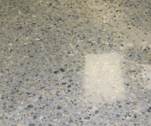 A close-up of USDA approved flooring reveals a polished concrete surface, showcasing small stones and pebbles embedded within, accented by two bright rectangular reflections from overhead lights. A close-up of USDA approved flooring reveals a polished concrete surface, showcasing small stones and pebbles embedded within, accented by two bright rectangular reflections from overhead lights.