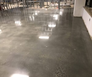 A smooth, polished concrete floor with a reflective surface features an industrial floor coating inside an unfinished commercial building, surrounded by partial walls and visible construction materials. A smooth, polished concrete floor with a reflective surface features an industrial floor coating inside an unfinished commercial building, surrounded by partial walls and visible construction materials.