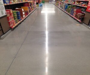A clean, shiny grocery store aisle lined with shelves stocked with various boxed and canned food products on both sides, featuring durable commercial kitchen flooring for a pristine and professional look. A clean, shiny grocery store aisle lined with shelves stocked with various boxed and canned food products on both sides, featuring durable commercial kitchen flooring for a pristine and professional look.