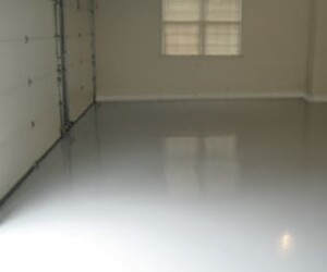 An empty garage with smooth, shiny gray resinous flooring CT, beige walls, two closed garage doors, and a window letting in natural light. An empty garage with smooth, shiny gray resinous flooring CT, beige walls, two closed garage doors, and a window letting in natural light.
