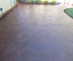 A backyard patio with a stamped concrete surface resembling natural stone, next to a house with light-colored siding and a garden bed along the edge, showcases durability similar to epoxy flooring Connecticut homes and businesses use for long-lasting appeal. A backyard patio with a stamped concrete surface resembling natural stone, next to a house with light-colored siding and a garden bed along the edge, showcases durability similar to epoxy flooring Connecticut homes and businesses use for long-lasting appeal.