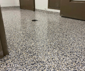 A shiny, speckled epoxy flooring Connecticut floor in a room with brown doors and white walls. The door is slightly open, and the space appears clean and empty with no furniture visible. A shiny, speckled epoxy flooring Connecticut floor in a room with brown doors and white walls. The door is slightly open, and the space appears clean and empty with no furniture visible.