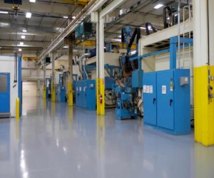 A clean, modern factory floor with blue industrial machines and yellow safety barriers features bright lighting and shiny resinous flooring CT. The area is organized and well-maintained, with pipes and cables overhead. A clean, modern factory floor with blue industrial machines and yellow safety barriers features bright lighting and shiny resinous flooring CT. The area is organized and well-maintained, with pipes and cables overhead.