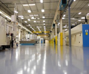 Bright, clean factory floor with overhead lights showcases a spacious area featuring large industrial machines and polished anti-slip epoxy floor. Equipment lines the sides, reflecting an organized workspace ideal for resinous flooring CT applications. Bright, clean factory floor with overhead lights showcases a spacious area featuring large industrial machines and polished anti-slip epoxy floor. Equipment lines the sides, reflecting an organized workspace ideal for resinous flooring CT applications.
