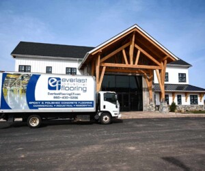 A white Everlast Industrial Flooring truck is parked in front of a large, modern building with wooden beams and a glass entrance, ready to deliver top-quality resinous flooring CT solutions on a sunny day. A white Everlast Industrial Flooring truck is parked in front of a large, modern building with wooden beams and a glass entrance, ready to deliver top-quality resinous flooring CT solutions on a sunny day.