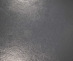 A close-up view of a dark gray, textured concrete surface with a slightly reflective, glossy finish, ideal for anti-slip epoxy floor applications and industrial floor coating in demanding environments. A close-up view of a dark gray, textured concrete surface with a slightly reflective, glossy finish, ideal for anti-slip epoxy floor applications and industrial floor coating in demanding environments.